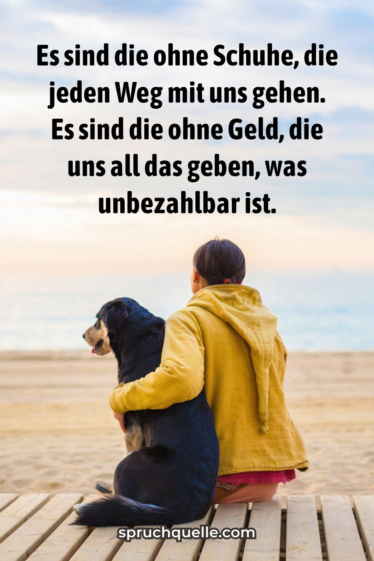 Frau und Hund sitzen zusammen am Strand und betrachten das Meer